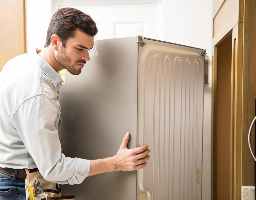 young-man-working-as-electrician-exposing-back-fridge-check-repair-it_662251-2712